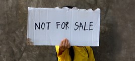 Child holding up a sign that says 'Not for sale'